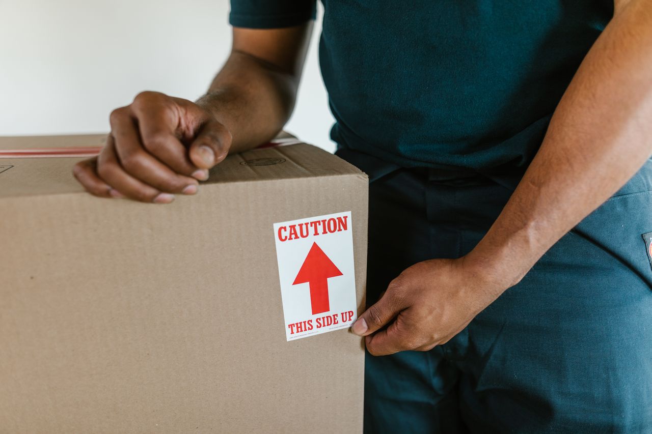 Mover carefully handling a packed box labelled this side up